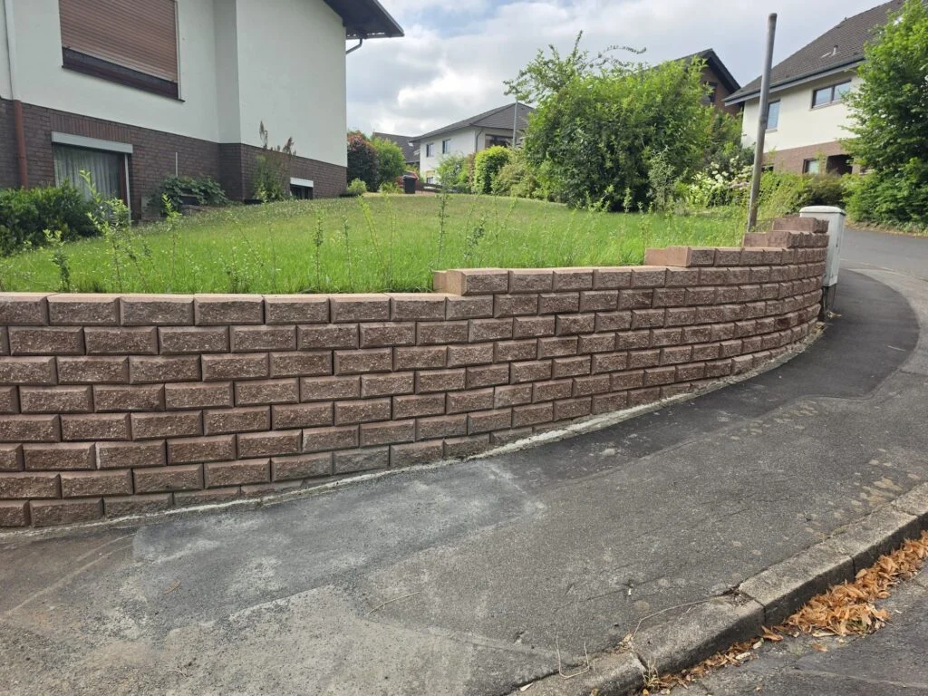 Gardoboss-Mauer in Herbstlaub, geschwungen entlang der Straße