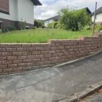 Gardoboss-Mauer in Herbstlaub, geschwungen entlang der Straße