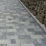 Bordsteinreihe als Kante zwischen Pflasterweg und Mauer