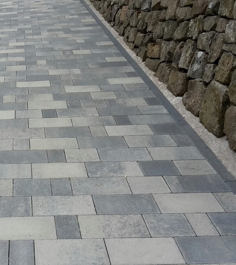 Bordsteinreihe als Kante zwischen Pflasterweg und Mauer