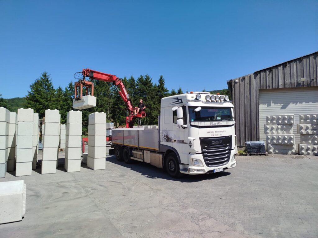 LKW mit Ladekran bei der Verladung von Betonblocks am Werk